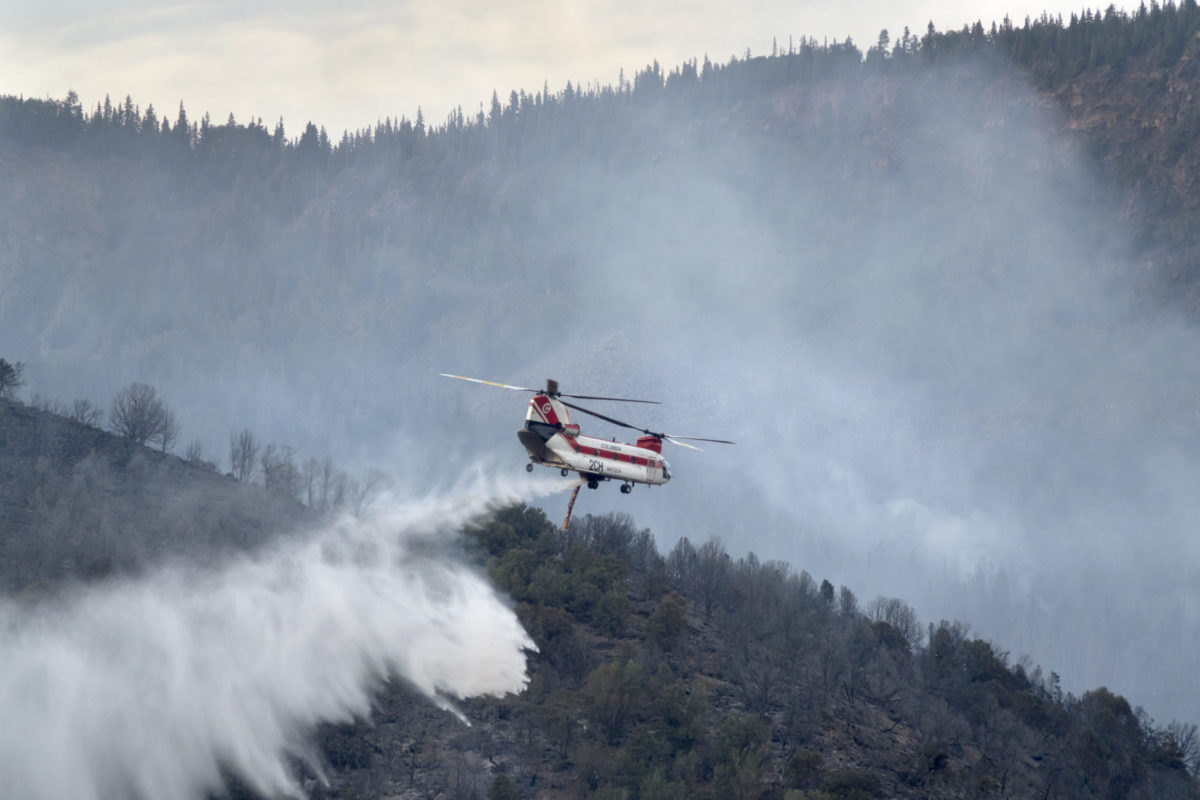 Flying low, a Chinook firefighting helicopter drops water over hotspots in the Lake Christine forest fire on Basalt Mountain above Highway 82 in the town of Basalt in Eagle County, Colorado on July 5, 2018.
